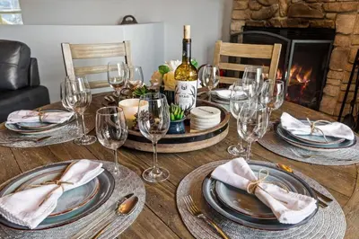 a table with wine glasses and plates and a fireplace at Panoramic Views at Deer Crest Lodge in Lake Arrowhead