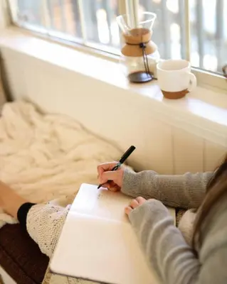 a woman writing in a notebook with a pen at Namu Cabin in Big Bear Lake