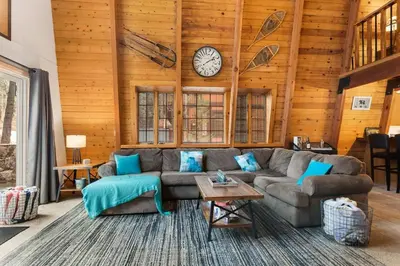 a living room with a couch and a clock on the wall at The 99 Pines Walk to Snow Summit Hot Tub in Big Bear Lake