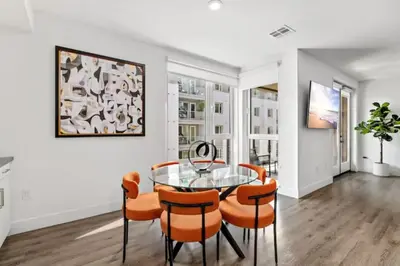 a dining room with a glass table and orange chairs at Ruby Tide - Two Floor Airy 2BR Marina Side Exclusive Amenities in Los Angeles
