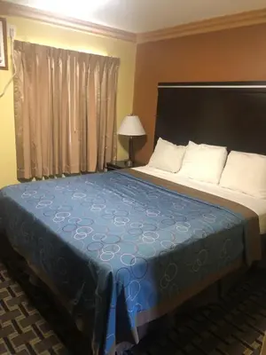 a bedroom with a large bed with a blue blanket at Glendora Motel in Glendora