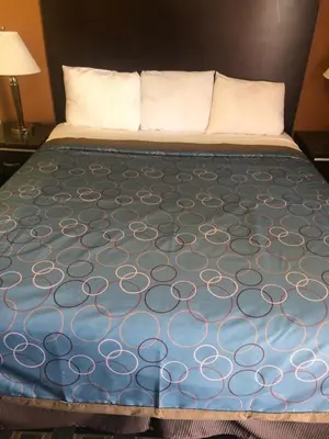 a bed in a hotel room with a blue blanket at Glendora Motel in Glendora