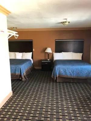 two beds in a hotel room with blue sheets at Glendora Motel in Glendora