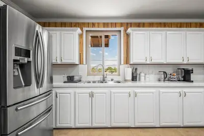 a kitchen with white cabinets and a stainless steel refrigerator at Luxury 6BR Retreat Fast WIFI, Dedicated Workspaces in Hesperia