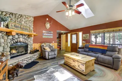 a living room with a large stone fireplace at Central Big Bear Lake Retreat with Private Hot Tub! in Big Bear Lake