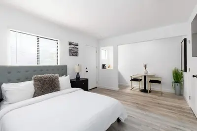 a white bedroom with a large bed and a table at Sunny Studio in the Heart of Venice - B in Los Angeles