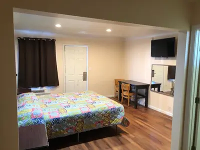 a bedroom with a bed and a table and a kitchen at Star Motel in Norwalk