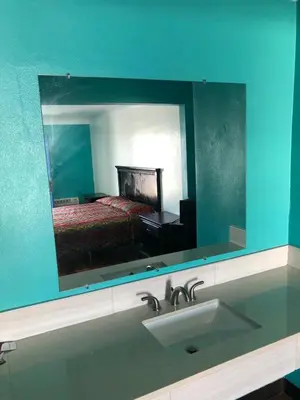 a bathroom mirror with a sink and a bed at Star Motel in Norwalk