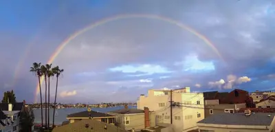 a double rainbow in the sky over a city at Peninsula Hideaway Apartment • Alamitos Bay in Long Beach