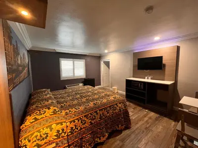 a bedroom with a bed and a sink and a television at The Patio Motel - Los Angeles, LAX in Gardena