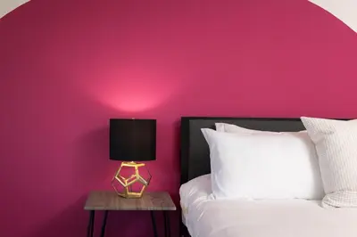 a pink bedroom with a bed and a table with a lamp at Fenix Hotel Hollywood in Los Angeles