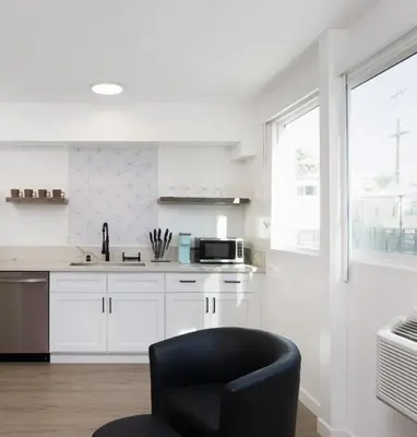a kitchen with white cabinets and a black chair at Fenix Hotel Hollywood in Los Angeles