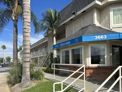 a hotel with palm trees in front of a building at Studio 6 Suites - Riverside, CA South in Riverside