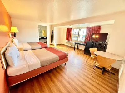 a hotel room with two beds and a table at Studio 6 Bellflower CA Los Angeles in Bellflower