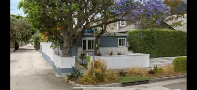 a blue house with a white fence and a tree at Chic Venice Beach Bungalow Steps from the Canals & Beach in Los Angeles