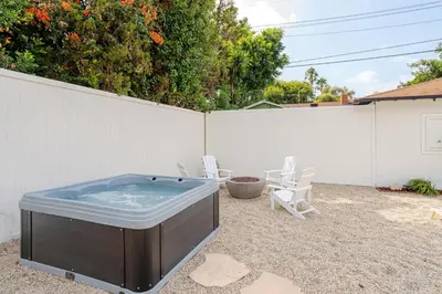 a hot tub in a backyard with chairs and a fence at Designer 2 bed near Universal sleeps 8 hot tub in Los Angeles
