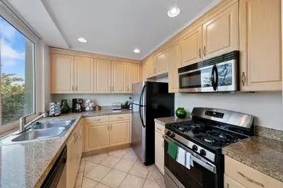 a kitchen with wooden cabinets and a black refrigerator at Beverly Hills Glamour Oasis 2 BR Apt with Parking 304 in Los Angeles