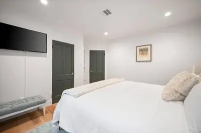 a white bedroom with a bed and a flat screen tv at Chic 3BR Oasis in Studio City:Toluca Lake Adjacent in Los Angeles