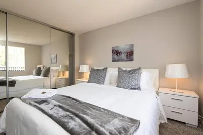 a bedroom with a large white bed and a mirror at Skyline Palms 1-Bedroom with Roof-Top Pool in Los Angeles