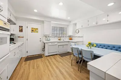 a kitchen with white cabinets and a table and chairs at Disneyland close FAMILY home! in Fullerton