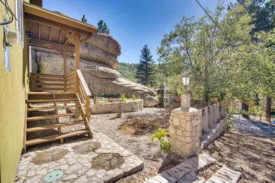 a house with a staircase leading up to a building at Running Springs Cabin with Spacious Deck and Hot Tub! in Running Springs