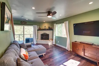 a living room with a couch and a flat screen tv at Running Springs Cabin with Spacious Deck and Hot Tub! in Running Springs