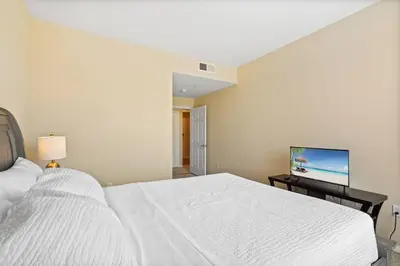 a bedroom with a white bed and a flat screen tv at Luxury 2BR/2BA! 5 MIN to Disney! in Anaheim