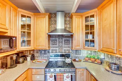 a kitchen with wooden cabinets and a stove top oven at 1 Mi to Lake Arrowhead Village! Cabin with Game Room in Lake Arrowhead