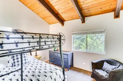 a bedroom with a bunk bed and a chair at 1 Mi to Lake Arrowhead Village! Cabin with Game Room in Lake Arrowhead