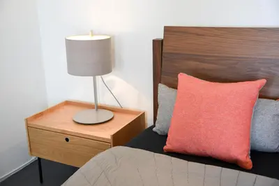 a bed with a red pillow and a lamp on a night stand at Hollywood Guesthouse in Los Angeles