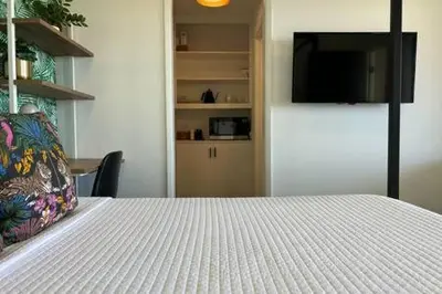 a bedroom with a white bed and a television at Ocean View Studio Manhattan Beach in Manhattan Beach