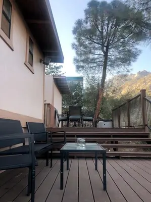 a deck with chairs and a table and a tree at Tillie Creek Retreat: a Creekside Oasis in Wofford Heights
