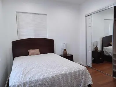 a white bedroom with a bed and a mirror at Achievers in Palmdale
