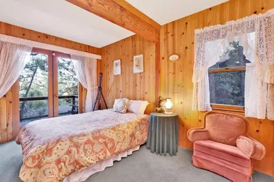 a bedroom with a bed and a chair and a window at Temple Lake Views Walk To Marina & Village Cabin in Big Bear Lake