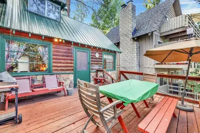 a wooden deck with a table and an umbrella at Temple Lake Views Walk To Marina & Village Cabin in Big Bear Lake