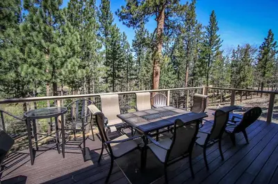 a wooden deck with a table and chairs on it at How Sweet It Is~ Downtown Village Retreat Cabin~ Walk to Marinas and Shopping in Big Bear Lake