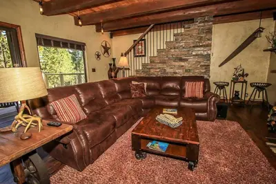 a brown leather couch in a living room with a table at How Sweet It Is~ Downtown Village Retreat Cabin~ Walk to Marinas and Shopping in Big Bear Lake