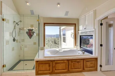 a bathroom with a tub and a shower with a window at Lake Arrowhead Home with 3 Decks and Stunning Views! in Lake Arrowhead