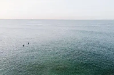 two people in the water in the ocean at Oceanfront Penthouse On Sand - Epic Views/Sunsets! in Huntington Beach