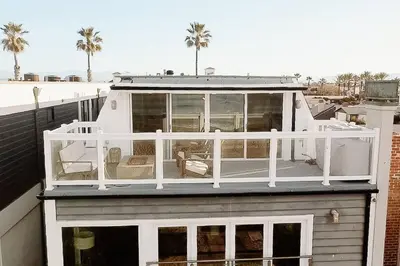 a house with a deck on top of a building at Oceanfront Penthouse On Sand - Epic Views/Sunsets! in Huntington Beach