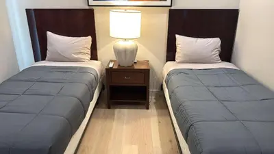 two beds in a room with a lamp on a night stand at Art District Downtown Spacious Homes in Los Angeles