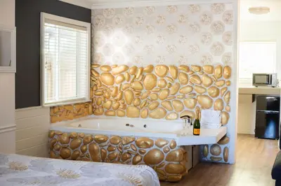 a bathroom with a tub with a wooden wall at Big Bear Spa Suites in Big Bear Lake