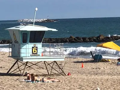two people laying on the beach near a life guard station at The Shores Inn in Ventura