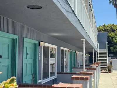a building with blue and green doors and benches at The Shores Inn in Ventura