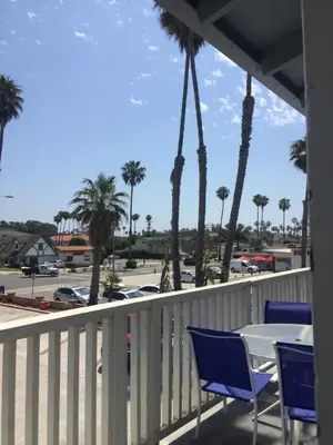 a table and chairs on a balcony with palm trees at The Shores Inn in Ventura