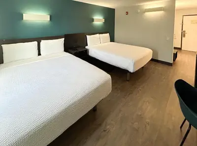 a hotel room with two beds and a chair at Studio 6 Suites Carson, CA in Carson