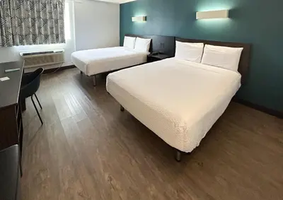 a hotel room with two beds and a desk and a desk at Studio 6 Suites Carson, CA in Carson
