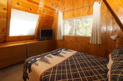 a bedroom with a bed and a television in a cabin at Kapers - Located in a beautiful quiet area of Big Bear Lake, walking distance to Snow Summit! in Big Bear Lake