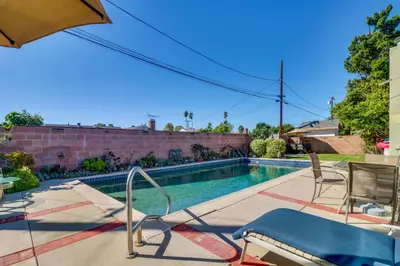 a swimming pool with chairs and an umbrella at North Hills Home with Outdoor Entertaining Space in North Hills