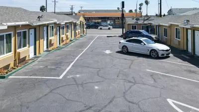 a white car parked in a parking lot next to buildings at SIGNAL HILL MOTEL BEACH MOTEL in Long Beach